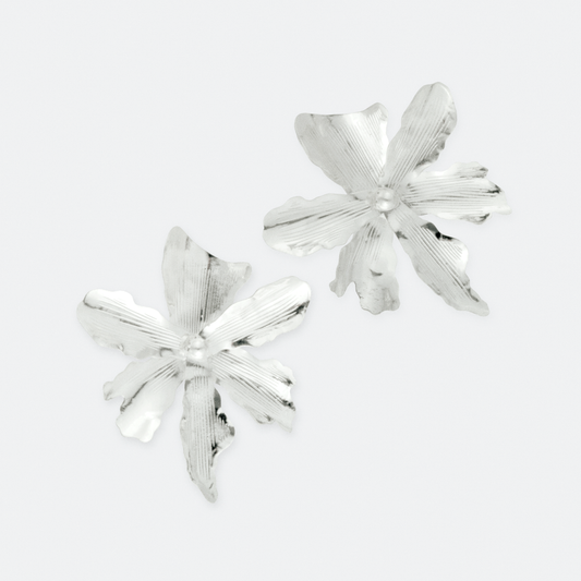 The Argentea earrings by Ocarina, handcrafted silver floral stud earrings with a delicate textured petal design. A bold yet elegant statement piece inspired by nature, displayed against a clean white background.