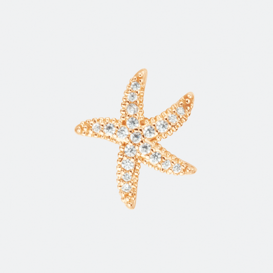 The Astra earring by Ocarina, an 18K gold-plated starfish-shaped stud adorned with shimmering zircon stones. A delicate ocean-inspired piece that captures the beauty of marine life, displayed against a clean white background