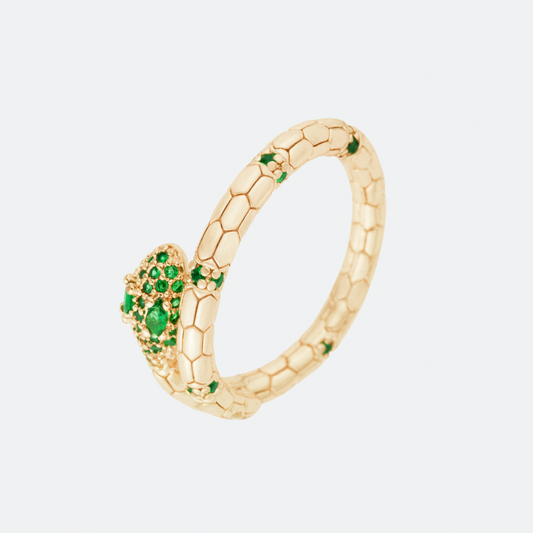 The Serpens ring by Ocarina, a gold-plated snake-inspired design with a textured scale pattern and embedded green gemstones. A bold statement piece symbolizing transformation and strength, displayed against a clean white background.